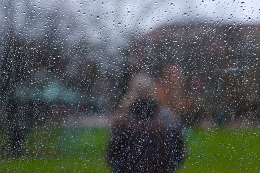 Raindrops on a window distort the view of a person outside in Gothenburg, Sweden.