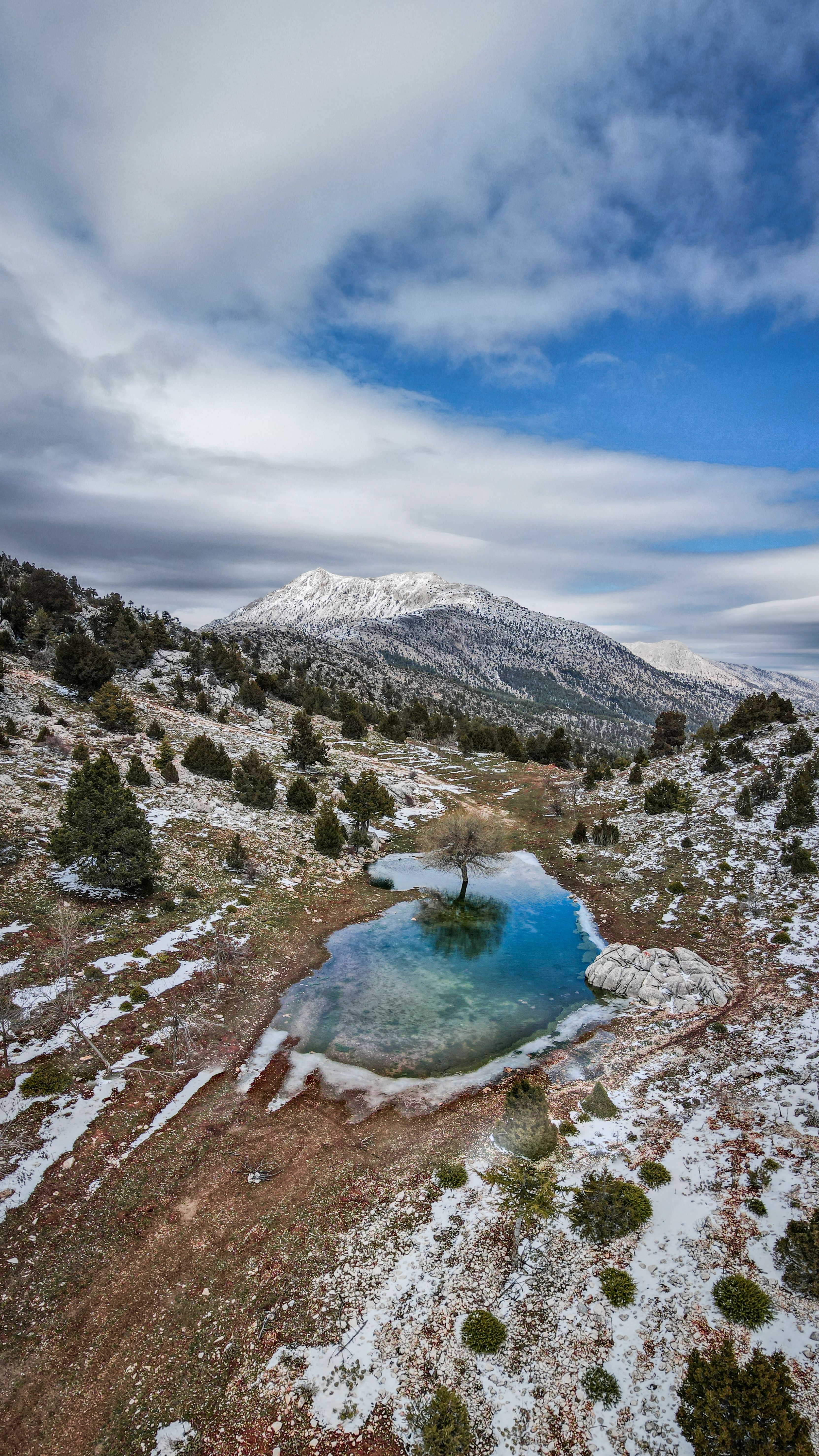 A stunning aerial view of a snowy landscape with a pond and mountains in Aziziye, Türkiye.