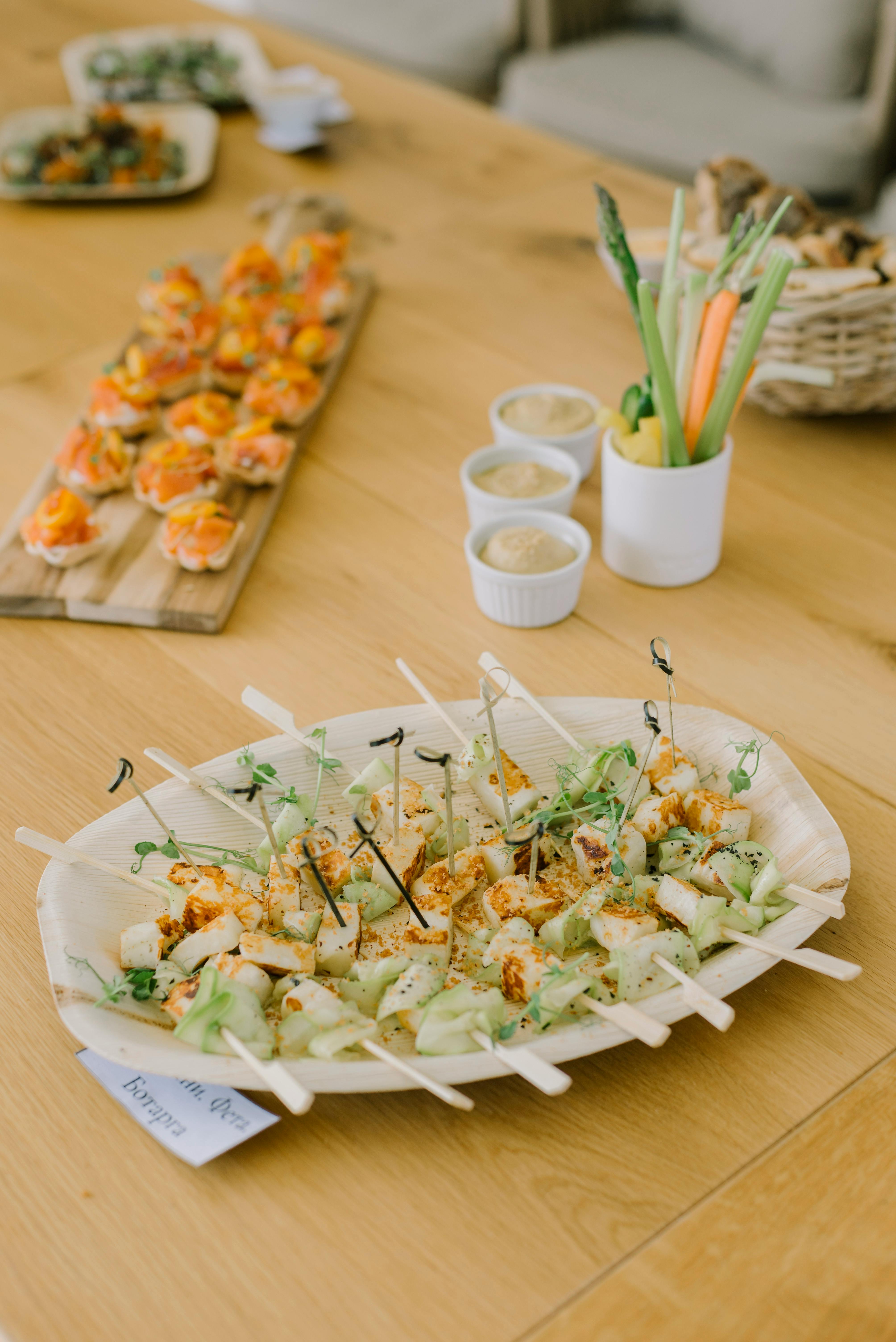 A visually pleasing assortment of healthy appetizers including skewers and vegetable dips on a wooden table.