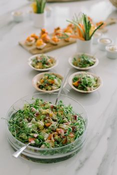 A healthy vegetable salad topped with microgreens on a table setting.