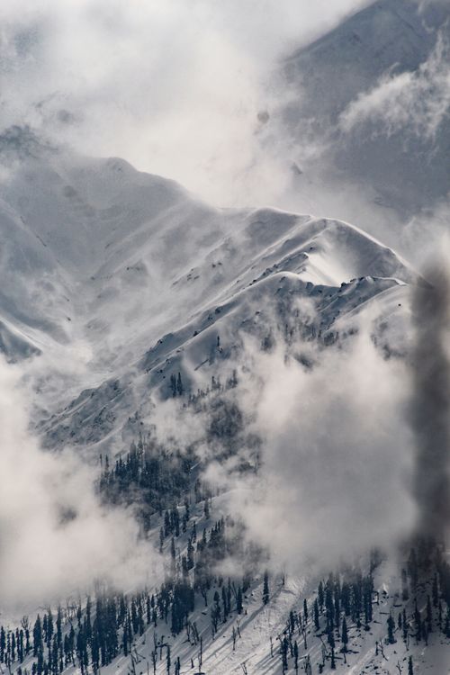 Free Breathtaking view of snowcapped mountains shrouded in fog, showcasing nature's raw beauty. Stock Photo
