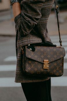 Fashionable woman with a designer bag, showcasing modern urban style in a street setting.