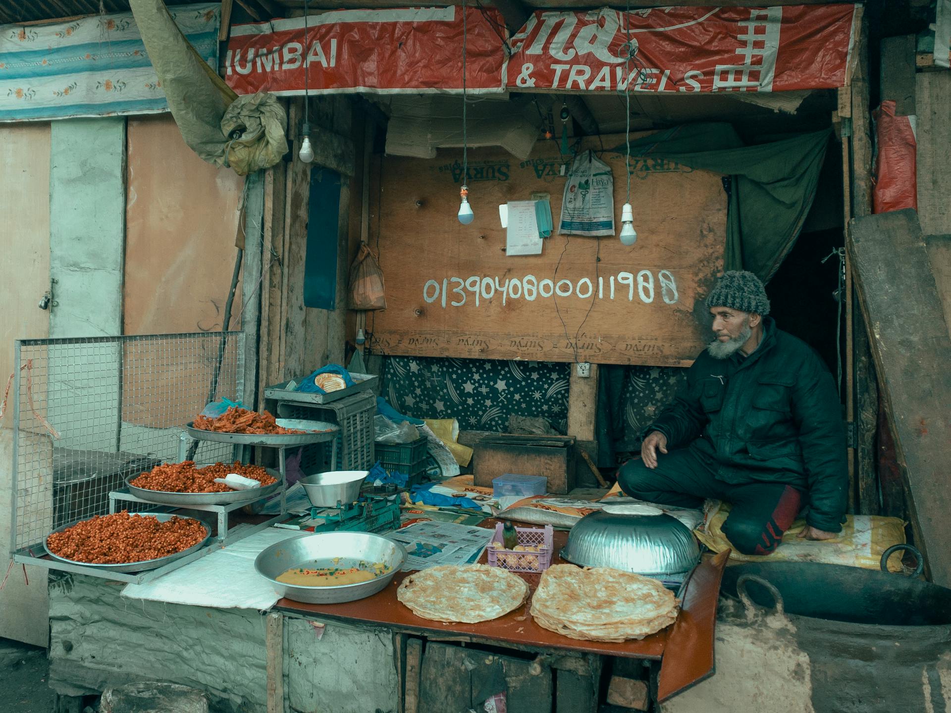 An elderly man sells traditional Indian food at an outdoor stall in JK street market.