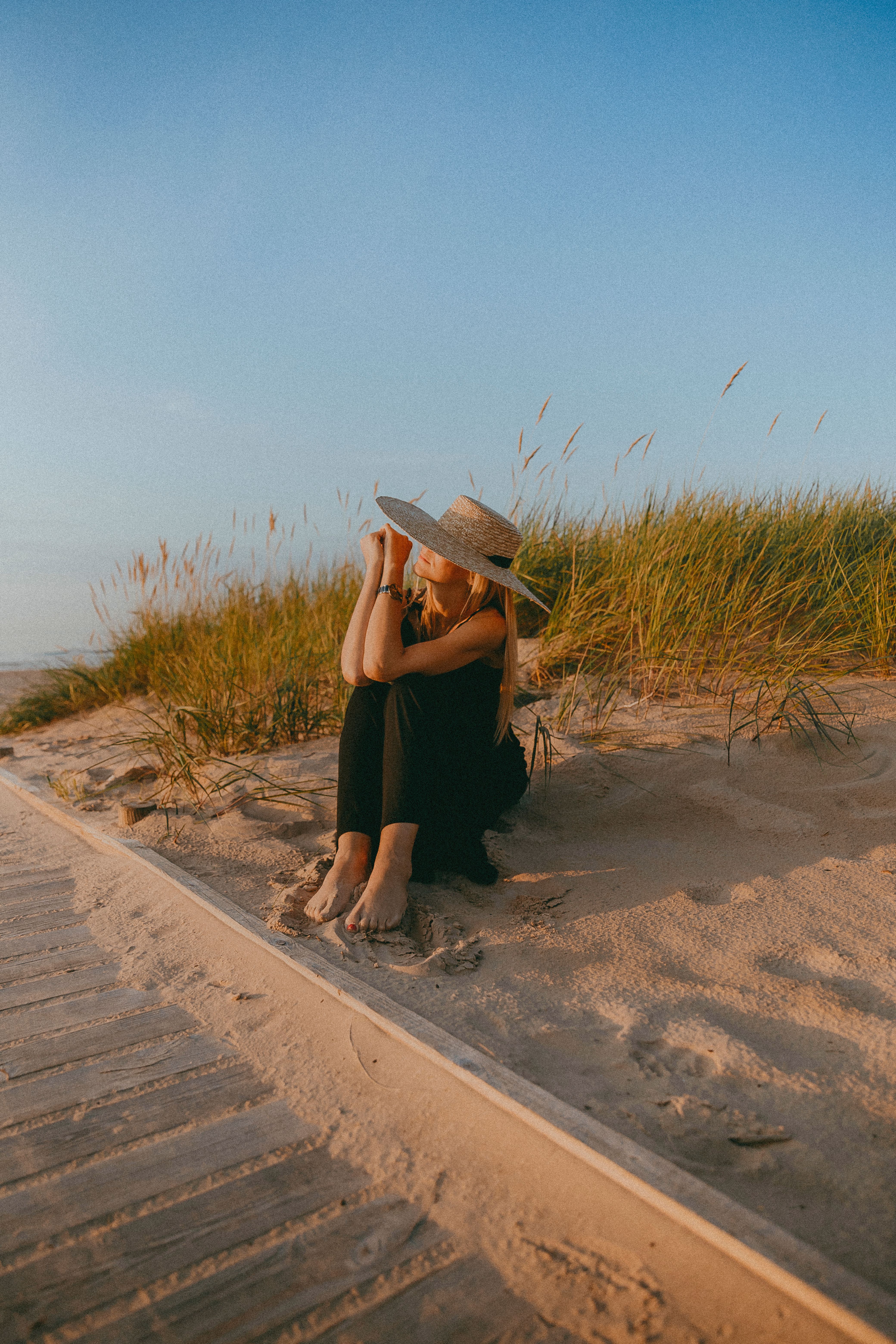 Woman in a Straw Hat Sitting on a Sandy Beach · Free Stock Photo