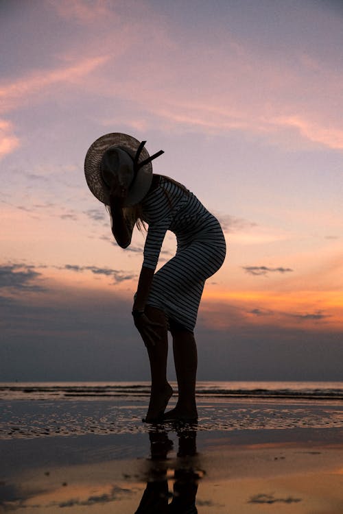 Free Silhouette of a Woman on the Beach at Sunset  Stock Photo