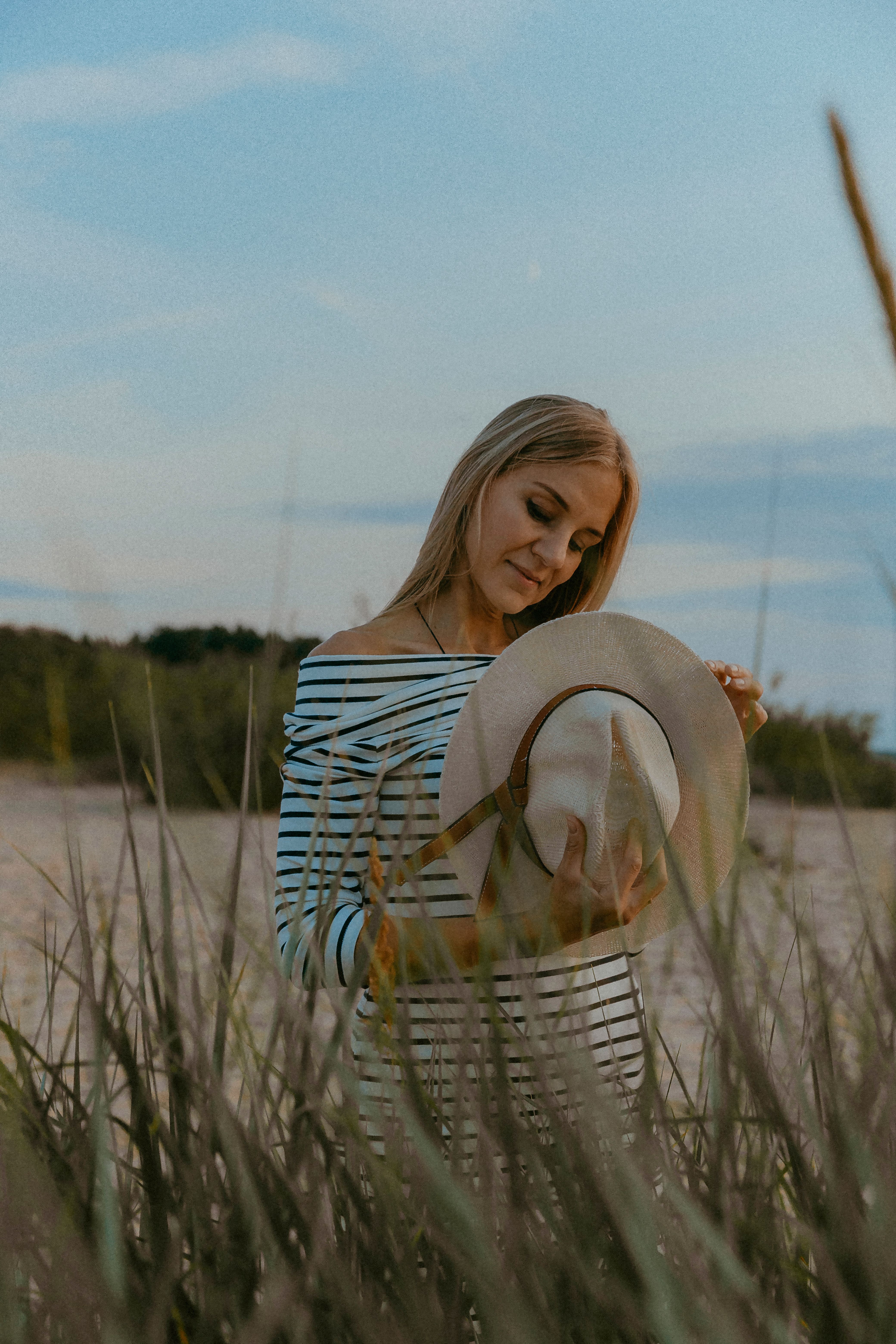 Woman in a Striped Dress Standing on the Beach and Holding her Hat ...