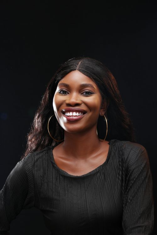 Free Charming portrait of a woman with long hair and earrings, smiling against a black background. Stock Photo