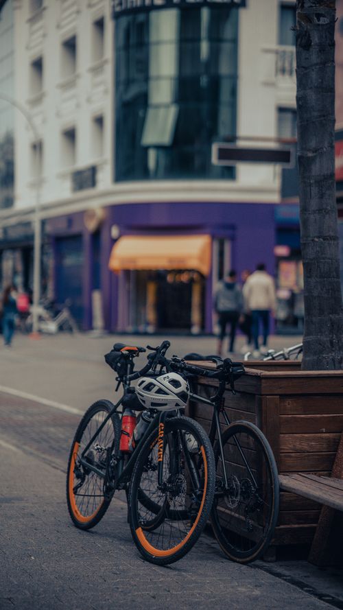 Free Two bicycles parked on a city street with pedestrians and modern buildings. Stock Photo