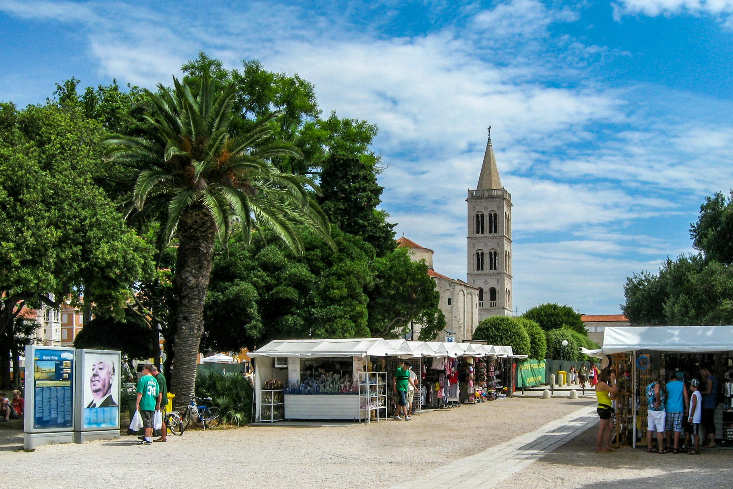 Lively market stalls and palm trees near the Church of St. Donatus in summer, Zadar, Croatia. by Sun Pixel Photography
