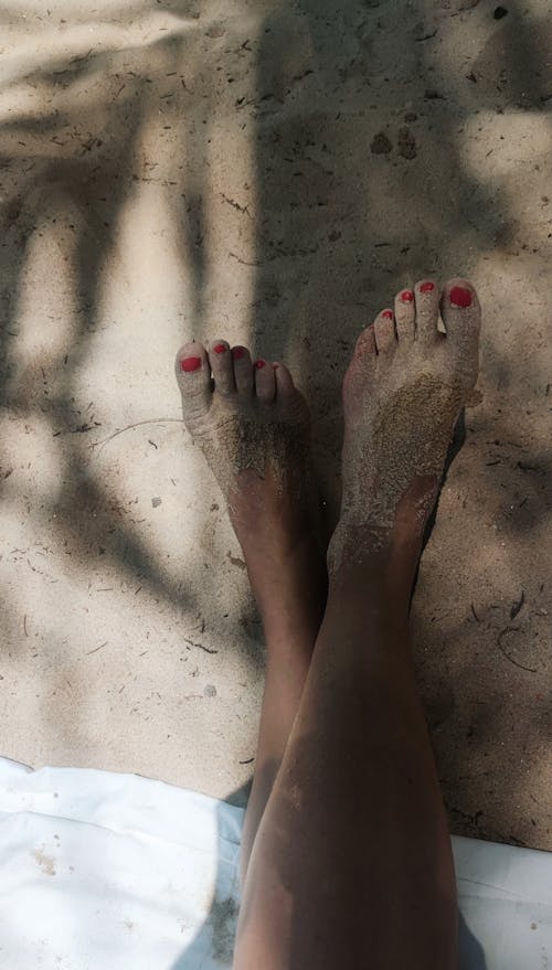 Free Woman Sitting on the Beach with Feet in the Sand  Stock Photo