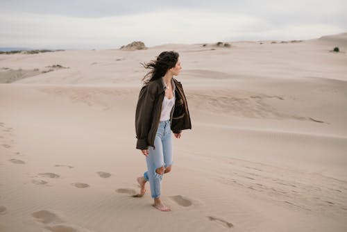 Woman Walking Barefoot through Sand