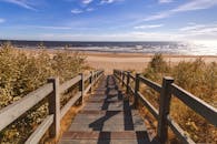 木制楼梯通向宁静的沙滩，在晴朗的蓝天下可以看到一望无际的海洋