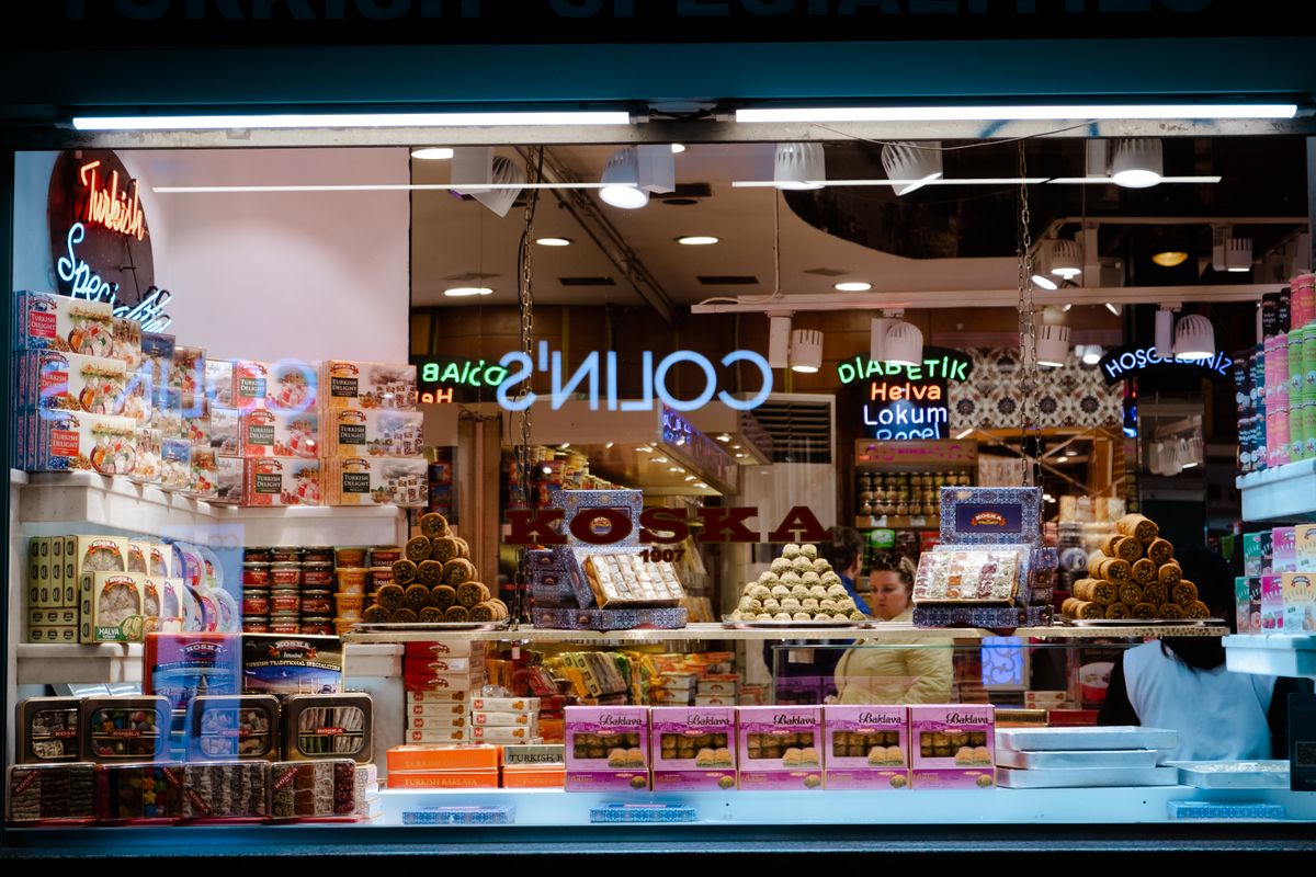 Colorful display of Turkish sweets in a shop window at night, featuring neon lights and variety of products.