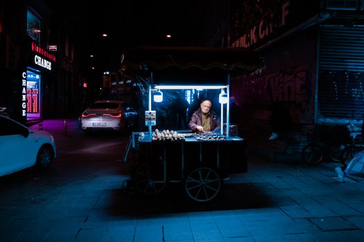 Street vendor selling roasted chestnuts at night in a vibrant urban street.