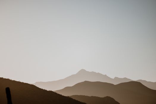 Peaceful silhouettes of mountains under a clear sky during a beautiful sunset.