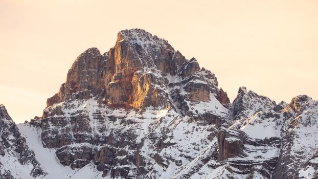 Stunning view of a snow-capped mountain peak during sunset with warm hues.