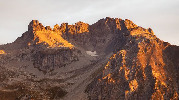 A breathtaking mountain peak illuminated by the warm glow of sunrise, offering a serene natural landscape.