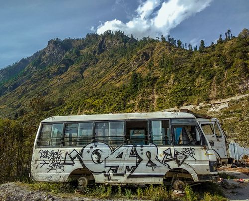 Free An abandoned graffiti-covered bus set against a scenic mountainous landscape under blue skies. Stock Photo