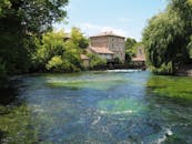 河边有一栋风景如画的乡村房屋，四周环绕着郁郁葱葱的绿树