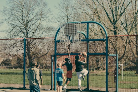 Group of kids playing basketball in an outdoor park court during the day.