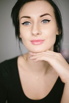 Close-up portrait of a woman with striking eye makeup and elegant pose.