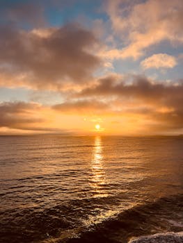Beautiful ocean sunrise with warm colors and dramatic clouds reflecting on the water.