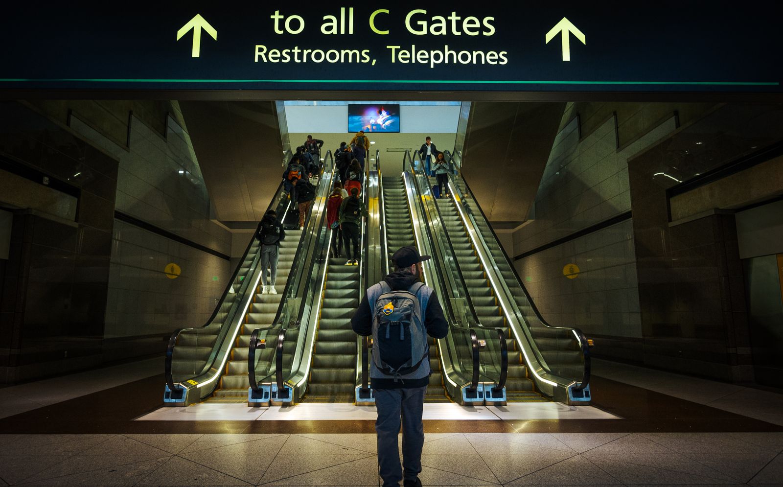 Passengers moving through an airport terminal escalator area