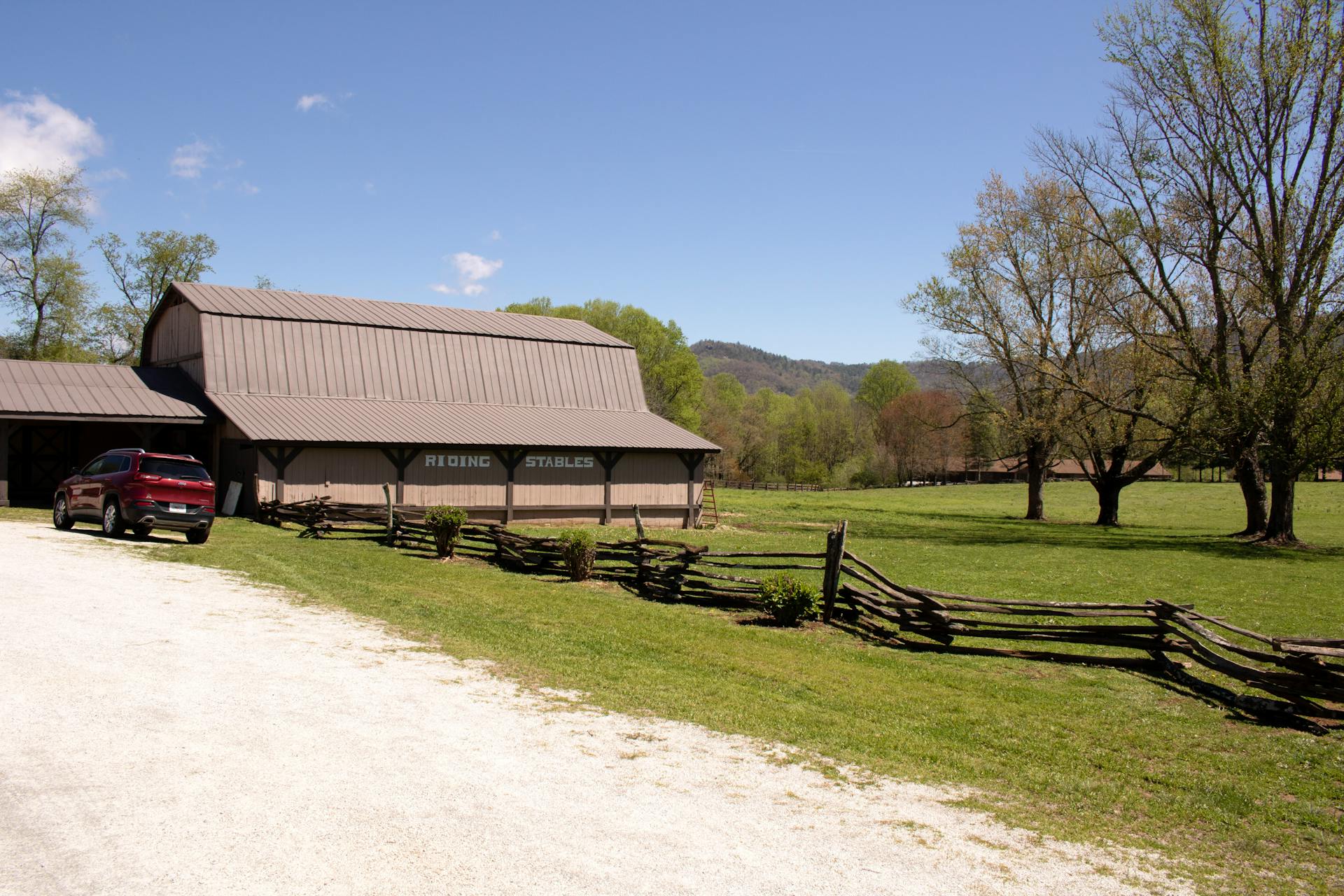 Quaint riding stables amid a rural landscape in Dillard, Georgia, under clear blue skies.