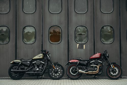 Free Two vintage motorcycles parked in front of an industrial-style garage with metal doors. Stock Photo