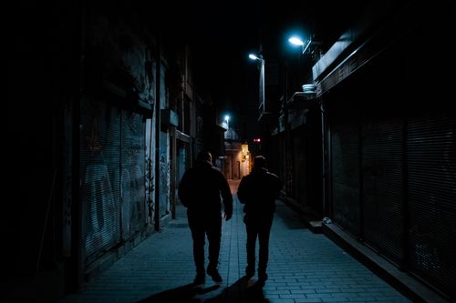 Free Two men silhouette walking in a dark urban alley at night with street lamps. Stock Photo