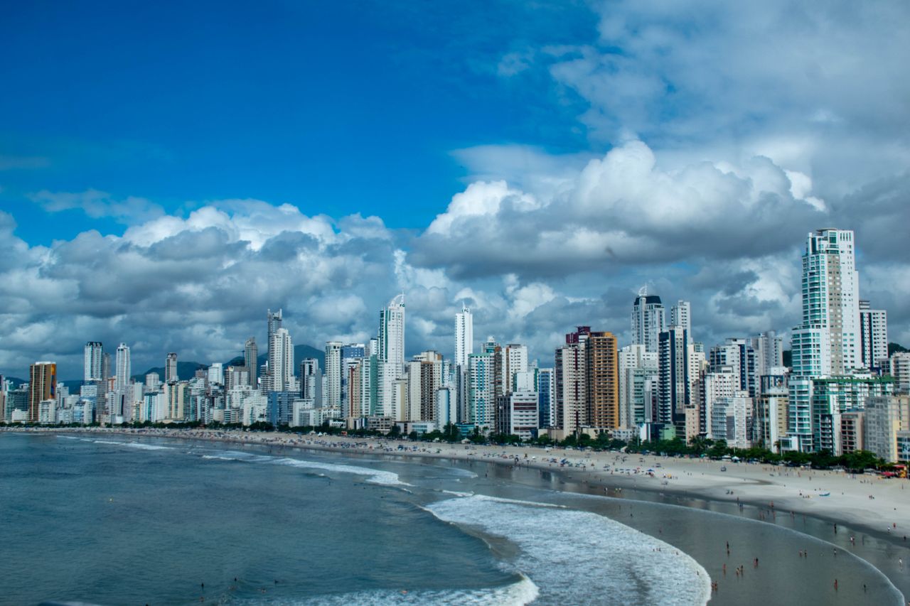 Captivating city skyline against a vibrant beach and sea, featuring towering skyscrapers and a dynamic oceanfront.