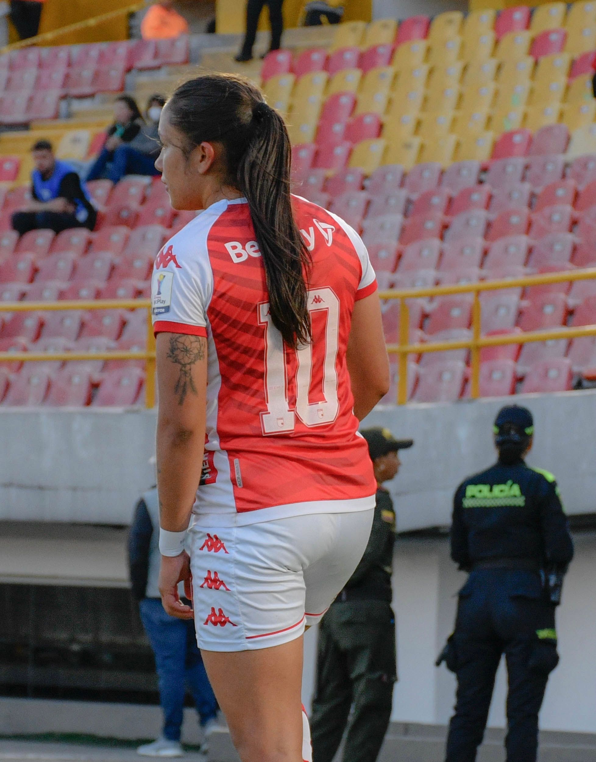 Back view of a female soccer player in a stadium during a match.