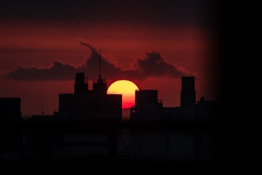A dramatic urban skyline silhouetted against a vibrant sunset sky creating a striking silhouette effect.