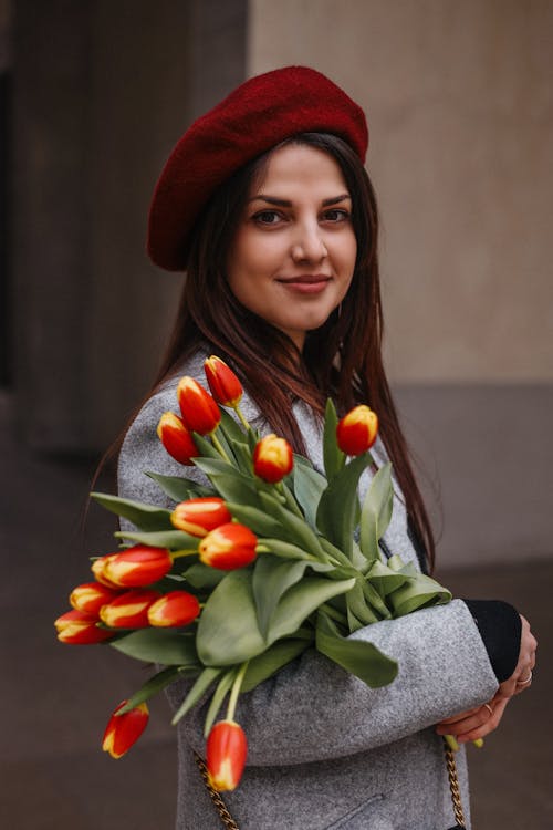 Young Brunette in a Red Beret Holding a Bunch of Tulips