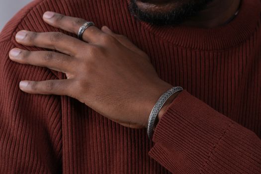 Close-up shot focusing on a man's hand adorned with elegant bracelets and rings.