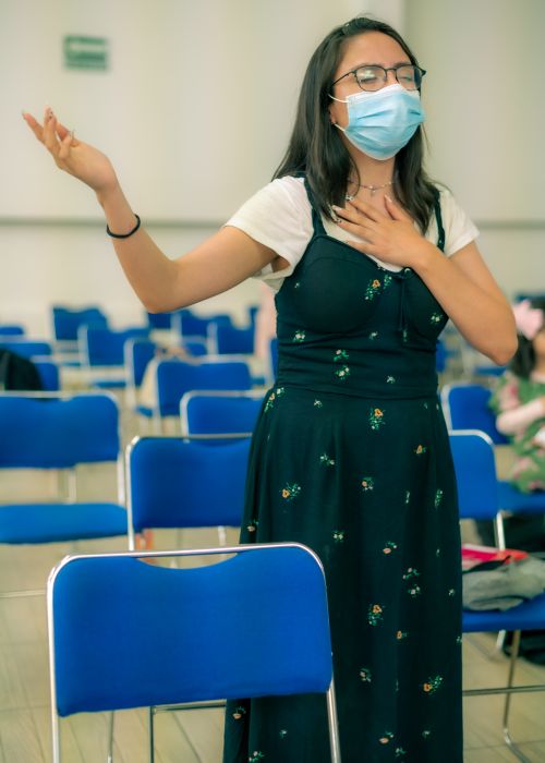Free Woman in a dress wearing eyeglasses and face mask, praying in church. Stock Photo