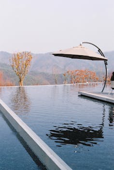 Infinity pool with umbrella offering scenic mountain view, perfect for a luxury vacation retreat.