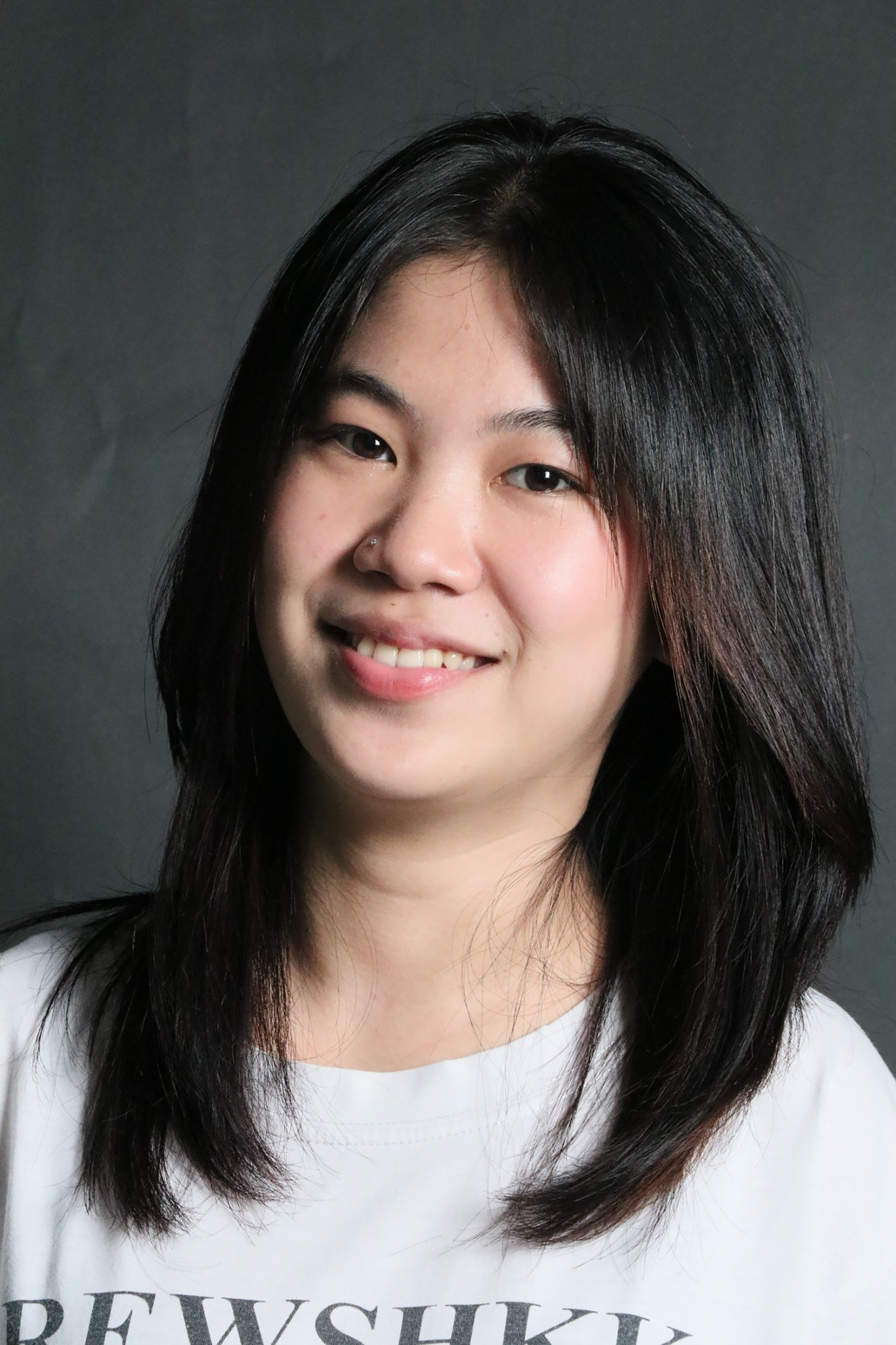Portrait of a smiling woman with long black hair against a dark background.