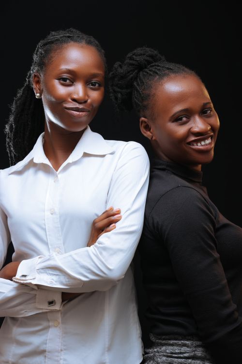 Free Two African American women posing confidently against a dark background, smiling and embracing friendship. Stock Photo