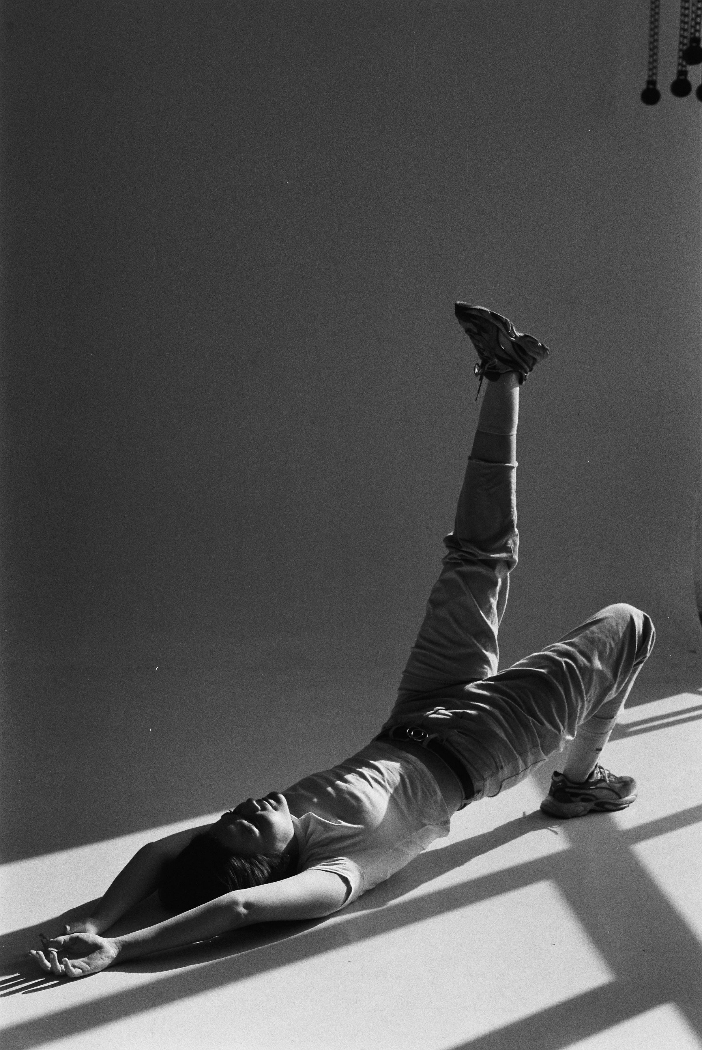 Artistic black and white portrait of a woman dancer in a studio, striking a dynamic pose.