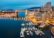 温哥华海滨暮光下的城市景观充满活力，拥有灯光明亮的码头和伯拉德桥