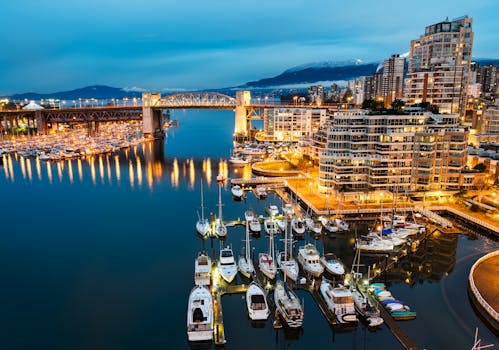 温哥华海滨暮光下的城市景观充满活力，拥有灯光明亮的码头和伯拉德桥