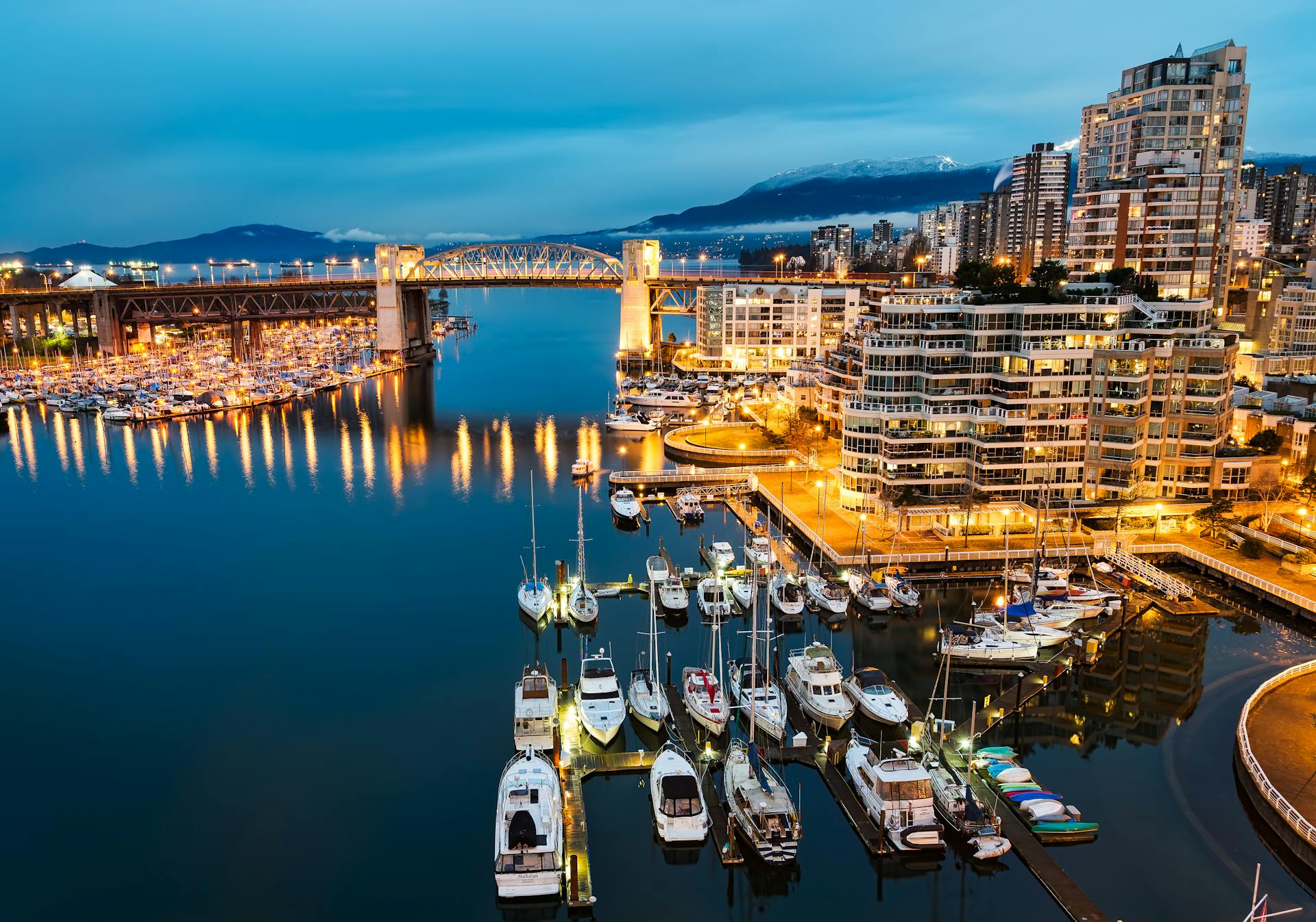 Vibrant twilight cityscape of Vancouver waterfront with illuminated marina and Burrard Bridge.