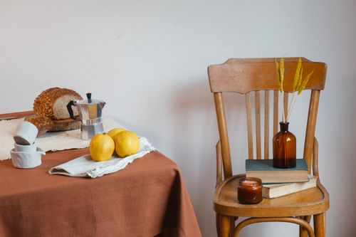 Free Warm interior setup with bread, quince, and decor on table and chair. Perfect for lifestyle or culinary themes. Stock Photo