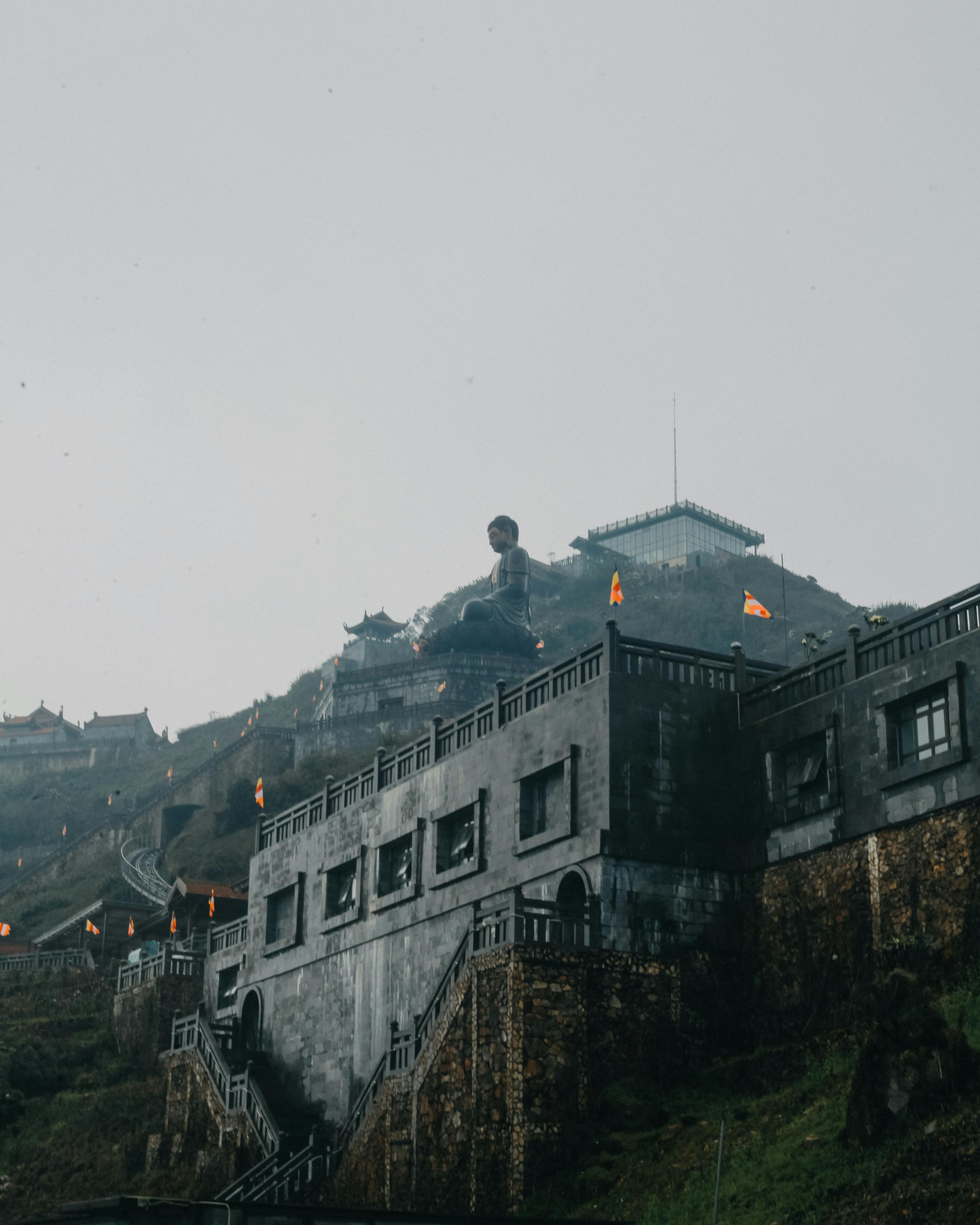 Captivating view of a temple and Buddha statue on Fansipan Mountain in misty Vietnam.