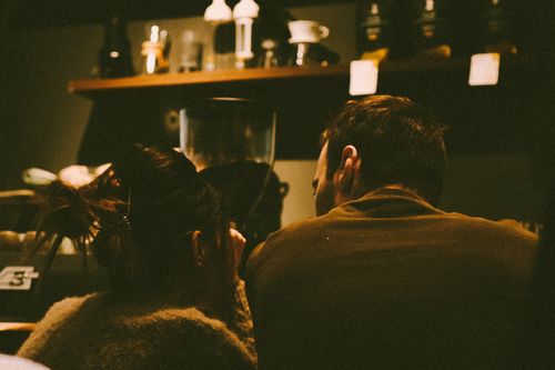 Free A couple enjoying a quiet moment at a dimly lit coffee bar. Stock Photo
