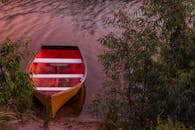 日落时分，一艘黄色的小船静静行驶在绿植环绕的河面上