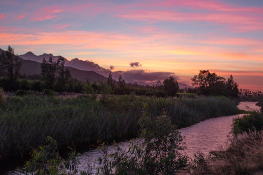 日落色彩缤纷，河流与山脉在自然摄影中展现出美丽的景观
