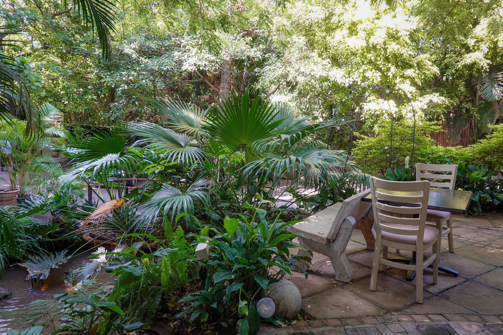 A lush tropical garden corner with outdoor table and chairs