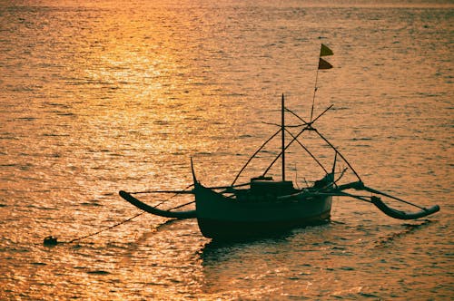 Silhouette of Boat Sailing in Water on Sunset